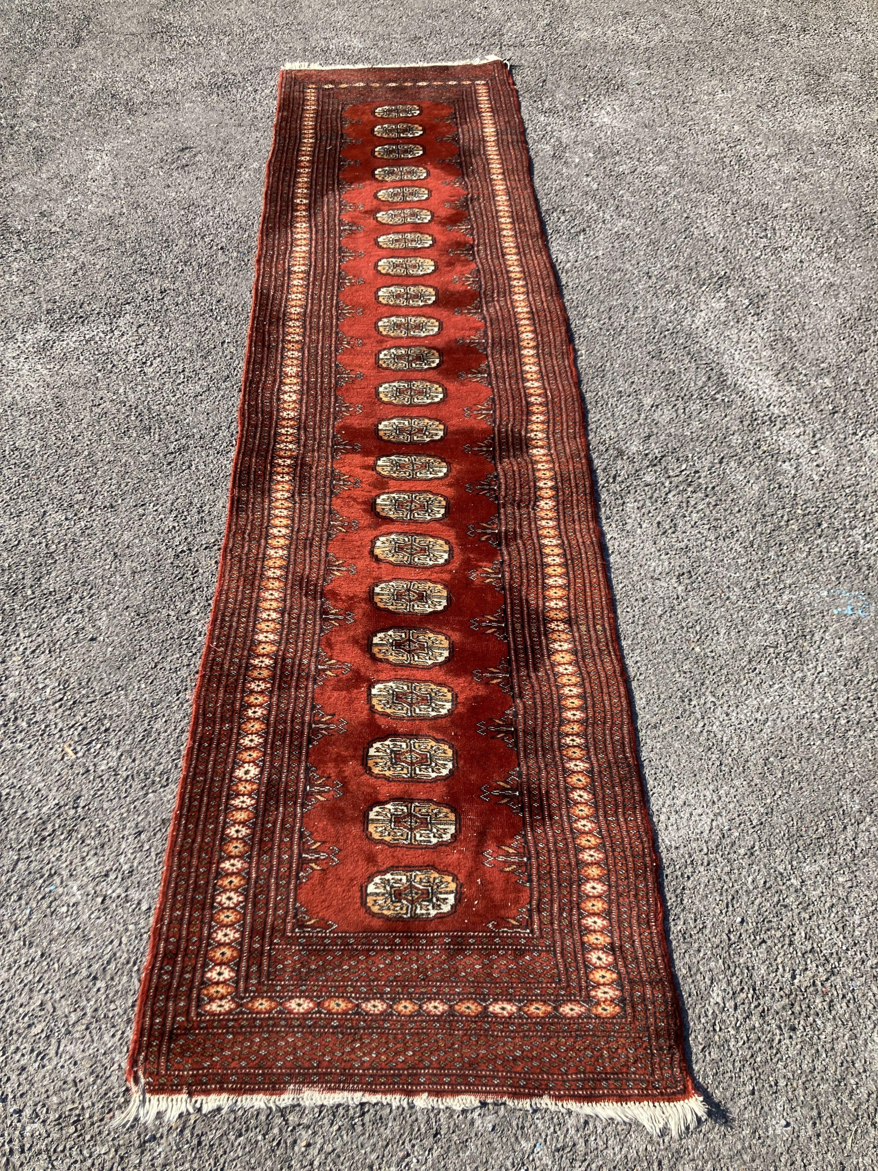 A Bokhara red ground runner with multi medallion field, 326 x 80cm